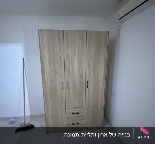 ארון עץ עם מגירות ומטאטא לידו